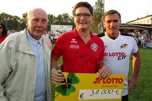 Fabian Pozywio (Mitte) mit dem Lotto-Spendenscheck und mit Fußball-Weltmeister Horst Eckel (links) sowie Europameister Stefan Kuntz.