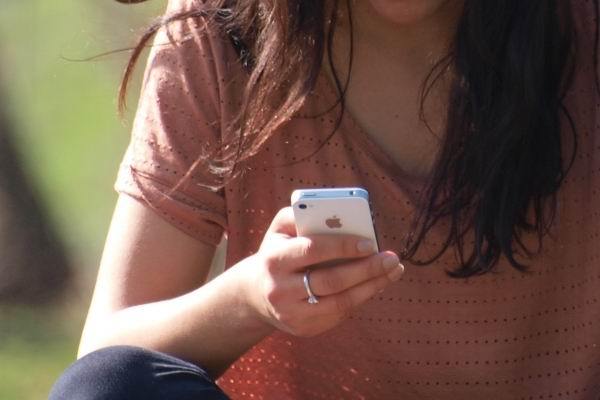 Junge Frau schreibt Textnachricht mit dem iPhone