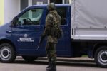 Soldat mit Waffe vor einem Bundeswehr-LKW mit der Aufschrift Wir. dienen. Deutschland.
