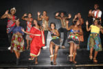 Tänzer und Sänger des UniZulu Choir in bunten Kleidern auf der Bühne