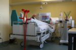 Patient mit Gipsbein im Krankenhausbett liest Zeitung