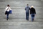 Drei Personen gehen eine Treppe hinauf